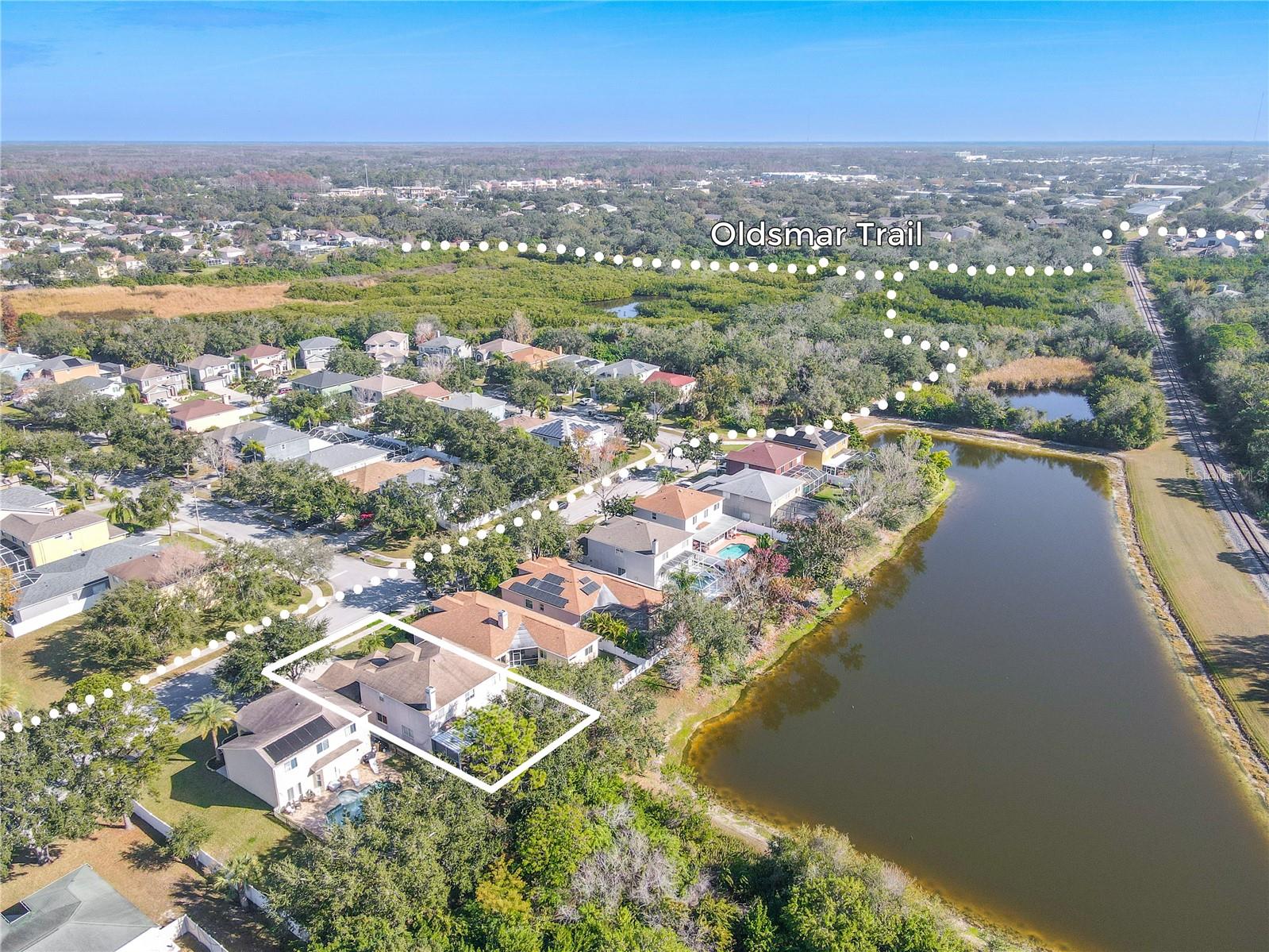 Sweeping aerial view shows the home just moments from the Oldsmar Trail, with serene water views and lush natural surroundings right nearby.