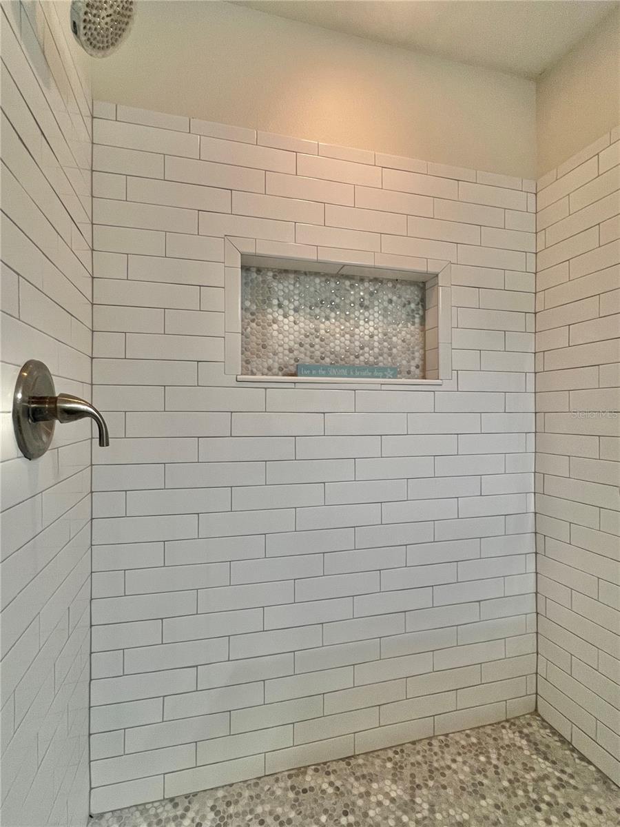 The primary walk-in shower was rebuilt with updated tile, flooring, hardware and an elegant niche shelf.
