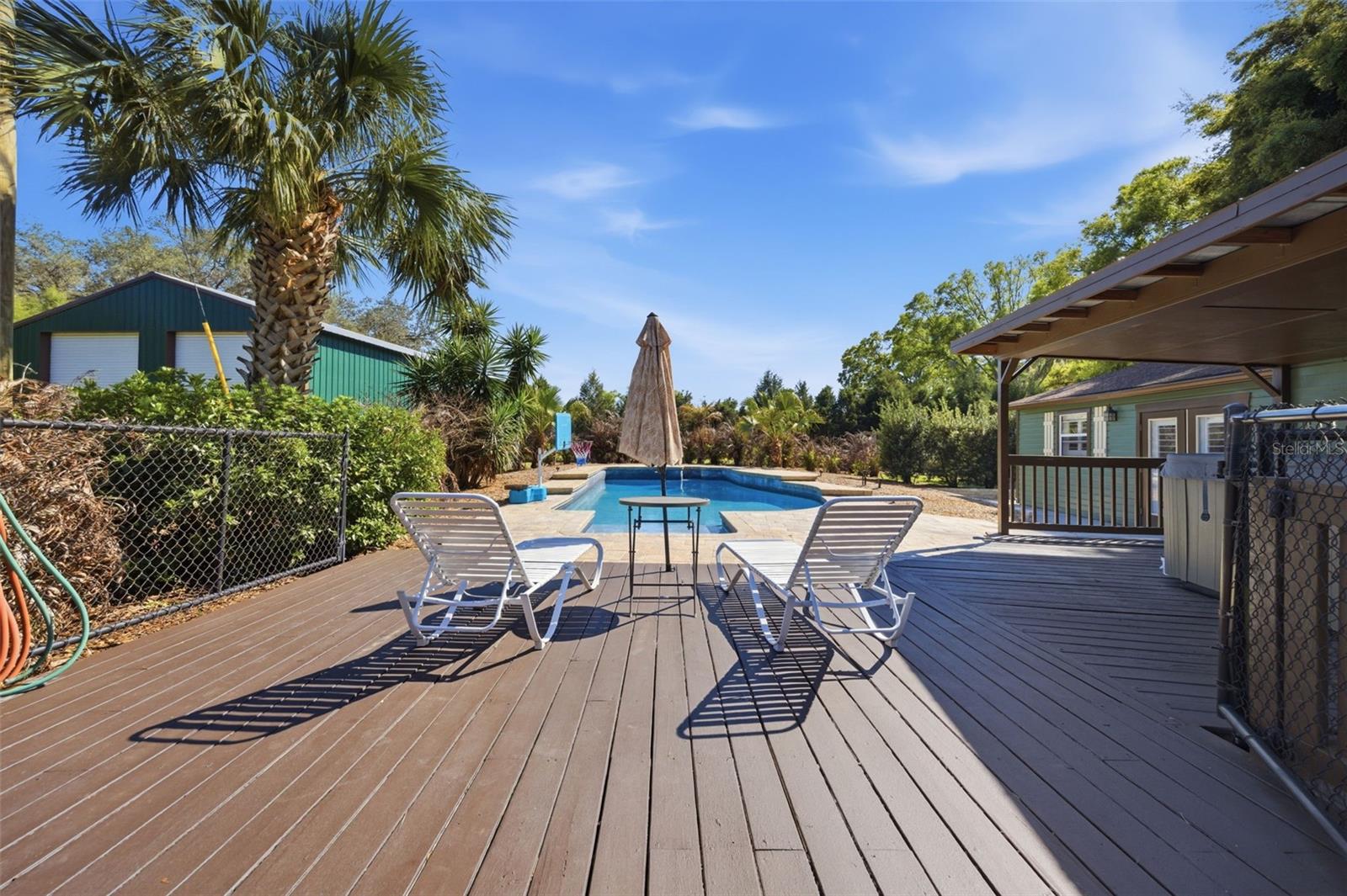Deck with hot tub to right and view of gorgeous pool