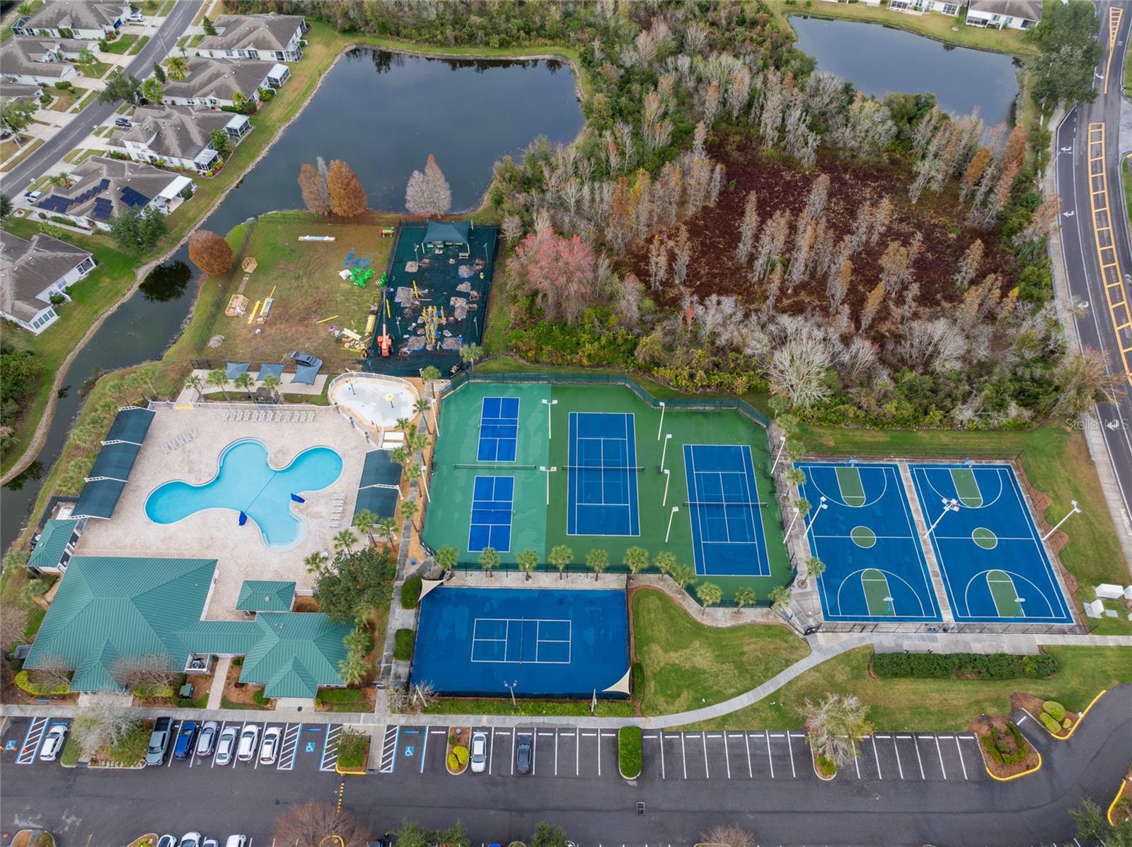 Aerial view of community pool, clubhouse, courts