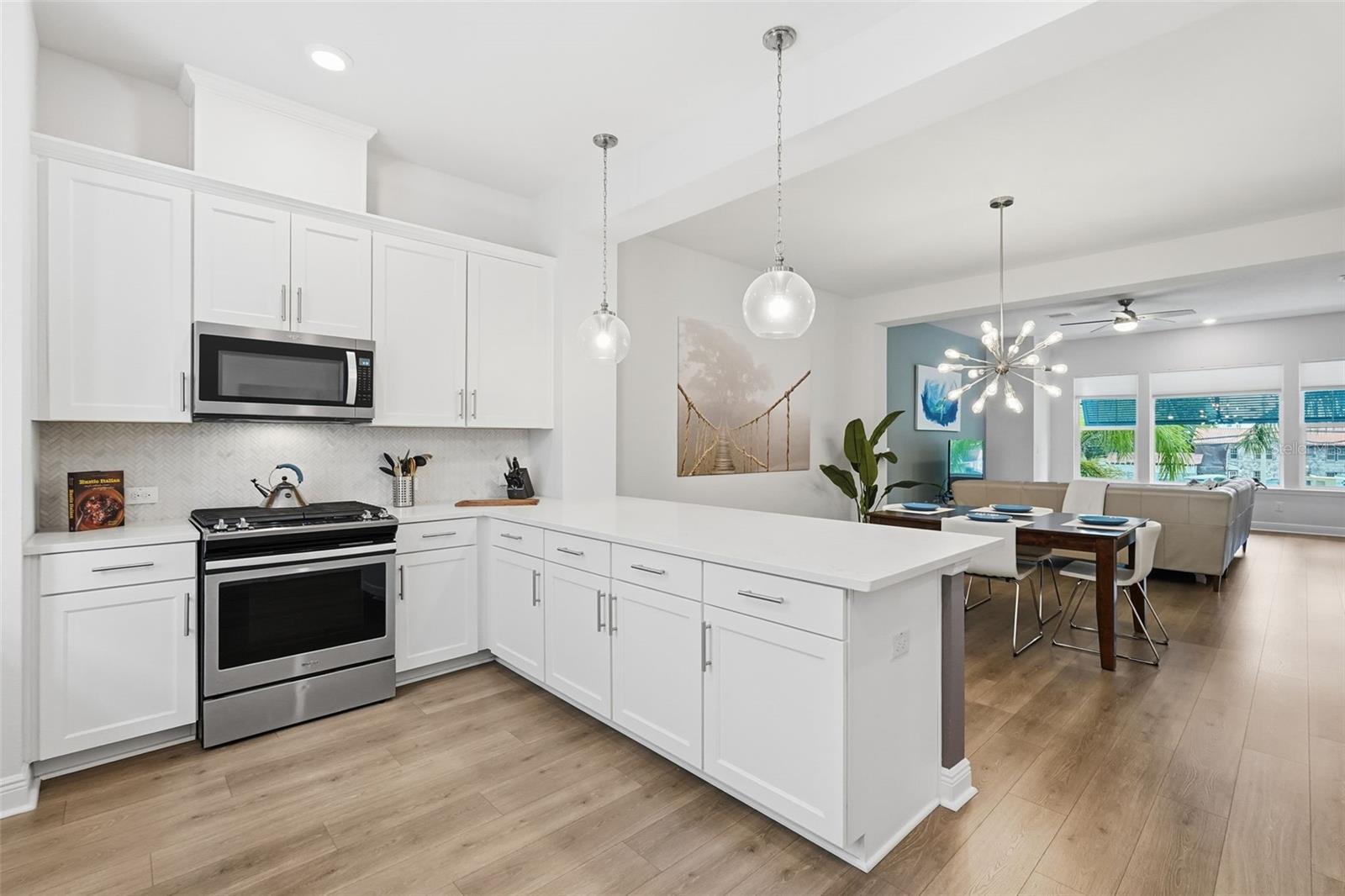 Kitchen with gas range, quartz counters, bar seating.