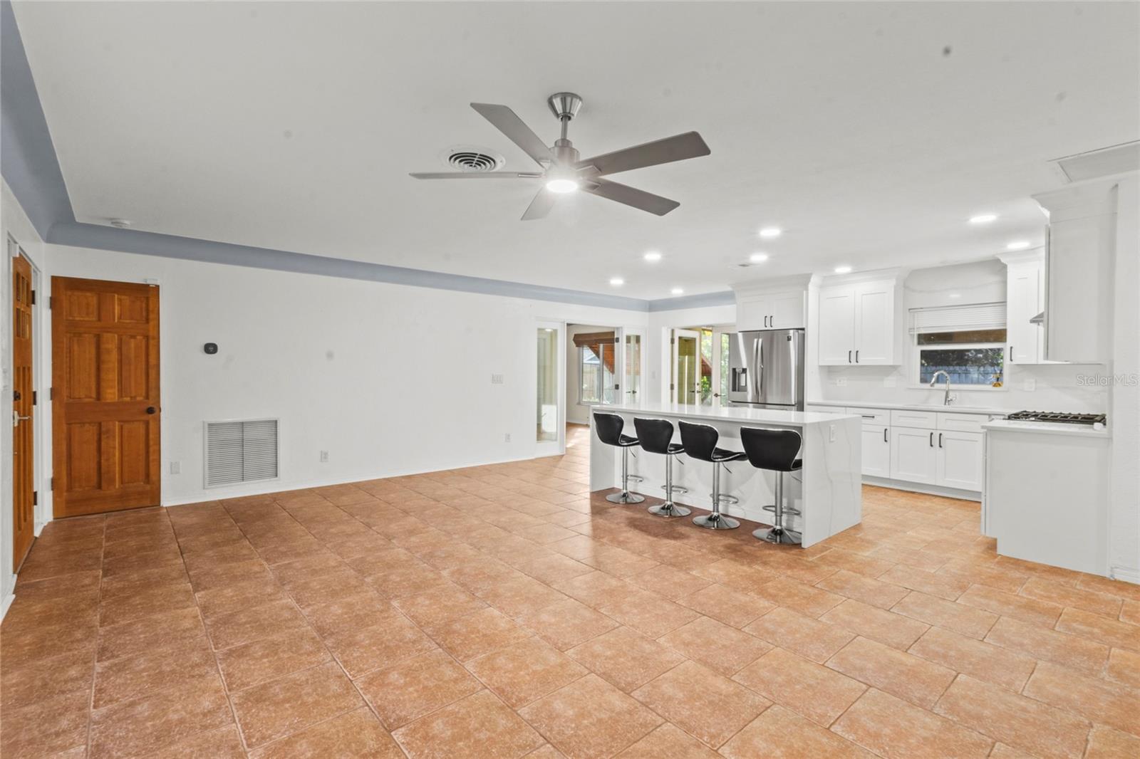Beautifully remodeled kitchen with large center island, quartz countertops, white shaker cabinetry, and stainless-steel appliances.