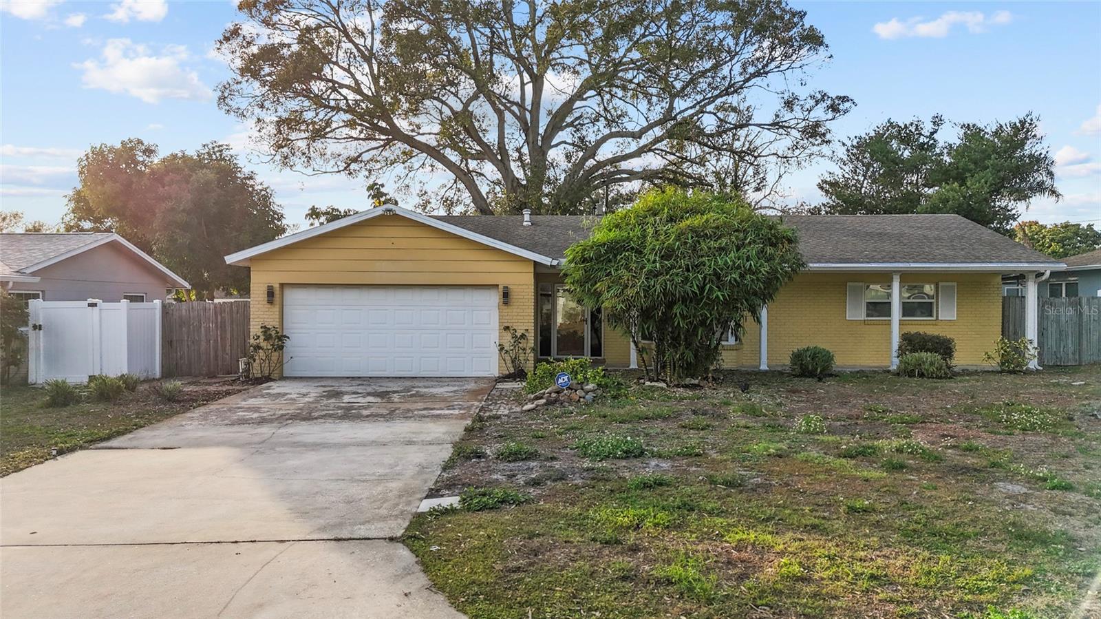 Charming single-story block home with wide driveway, 2-car garage, and mature shade trees in a quiet, established St. Petersburg neighborhood.
