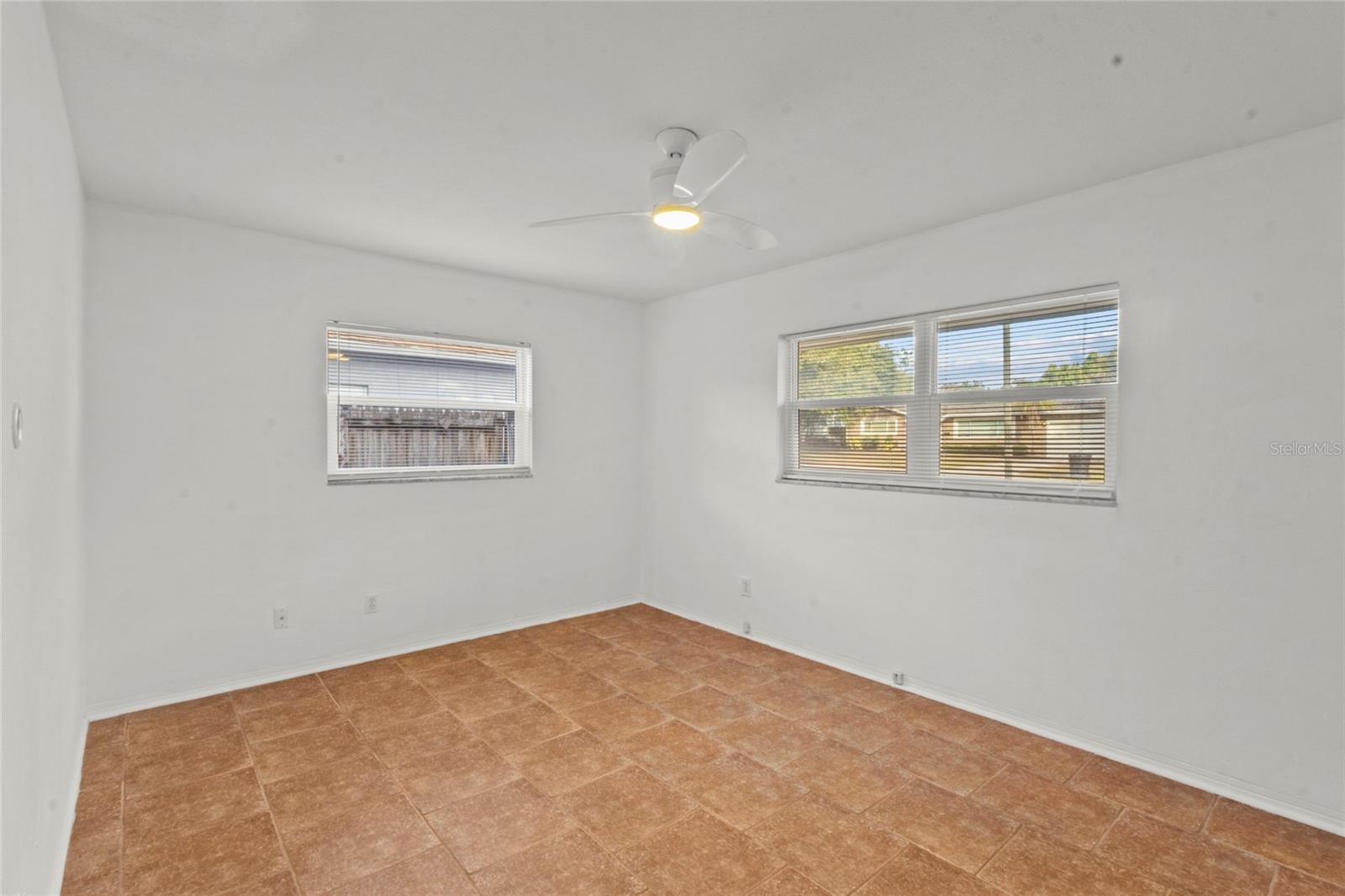 Primary Bedroom – Generously sized primary suite with tile flooring, ceiling fan, and abundant natural light.
