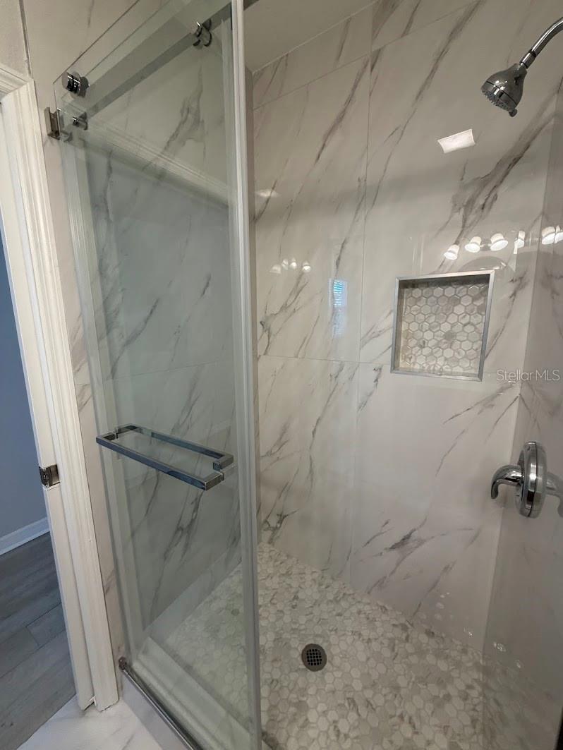 Sleek walk-in shower with polished tile surround and a convenient niche.