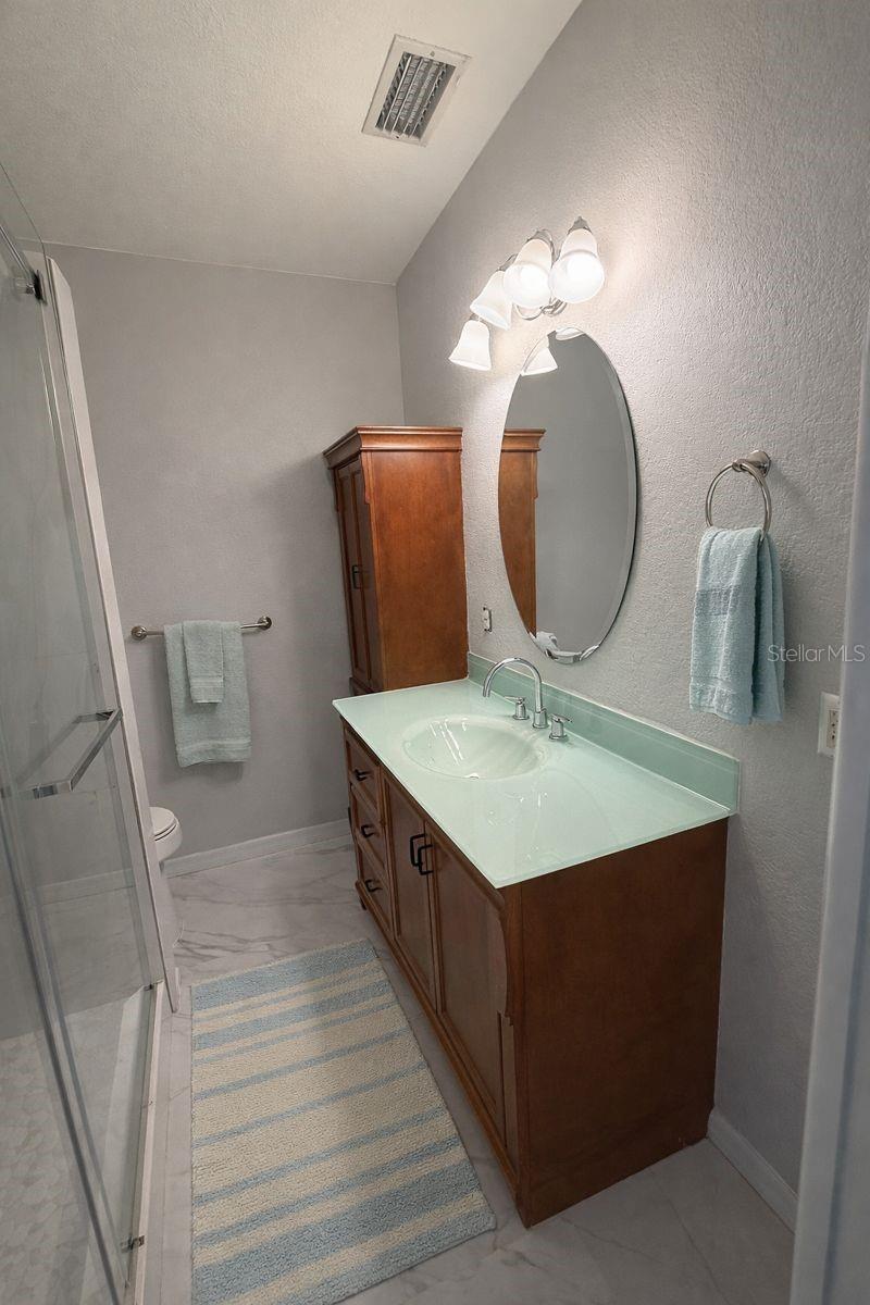 The primary, ensuite bathroom, has been updated with lovely tile, rich cabinents, clear glass shower doors and lovely tiles!