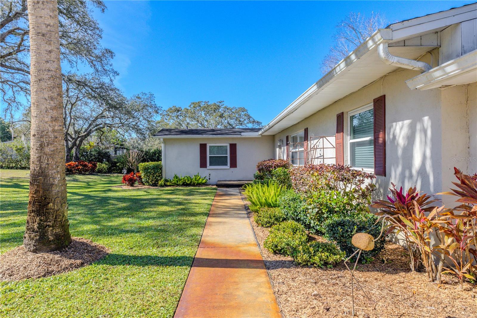 Inviting front walkway bordered by established landscaping, leading to the covered entry and main living areas.