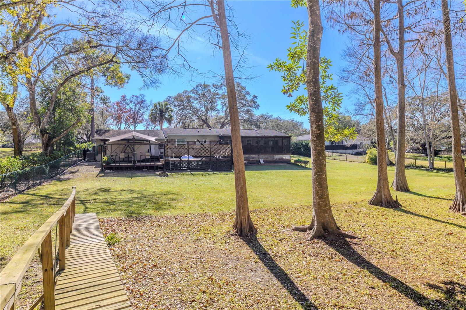 Peaceful backyard setting with an expansive lawn framed by mature trees, creating a private, park-like atmosphere.