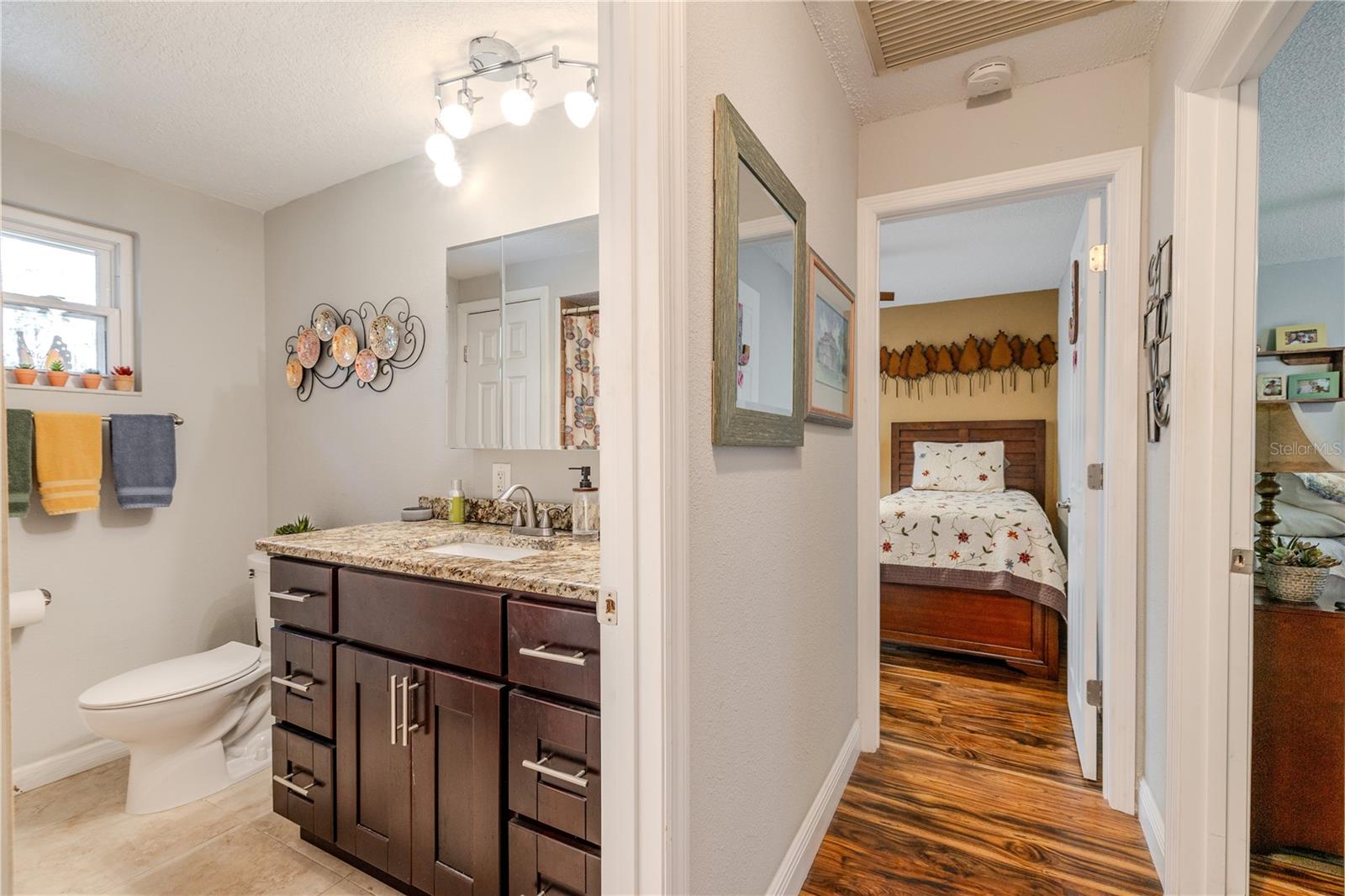 The Second bathroom has a granite countertop, dark wood vanity, updated fixtures, and convenient hallway access.