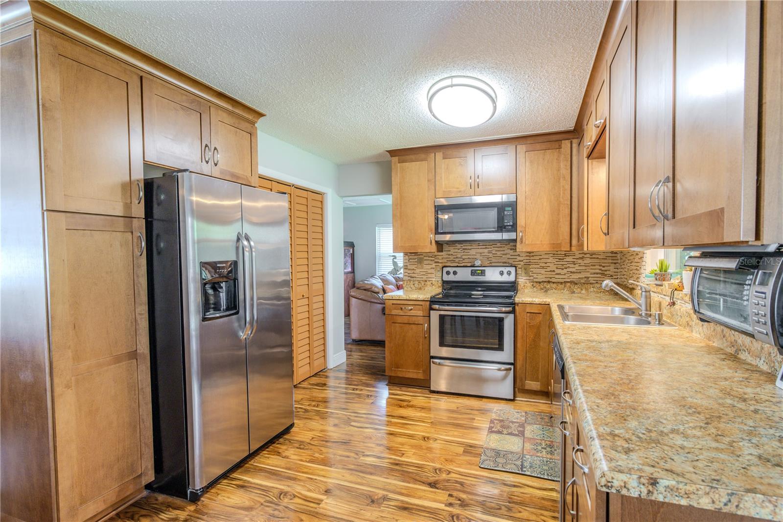 Spacious kitchen showcasing abundant cabinetry, stainless steel appliances, and a clear sightline into the living room, reinforcing the home’s connected floor plan.