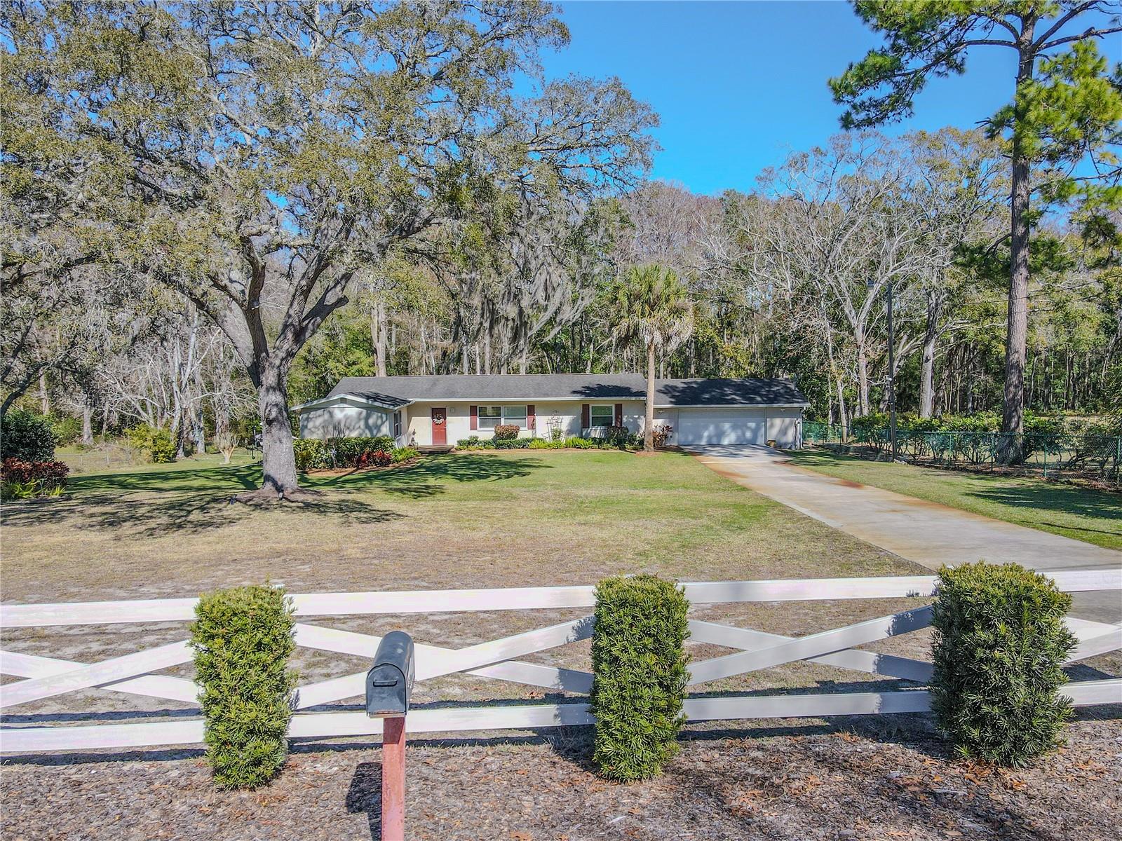 White cross-rail fence along the front of the property, offering a classic ranch-style look and a clear sense of entry.