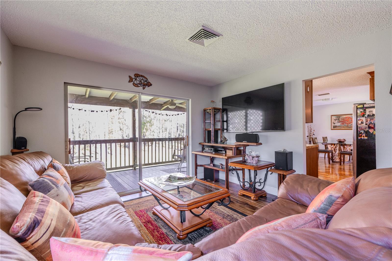 Comfortable family room offering a clear sightline into the kitchen and dining areas, reinforcing the home’s open, connected layout. The space features laminate flooring, ceiling vents for efficient airflow, and a natural flow that makes moving between living, dining, and kitchen areas effortless.