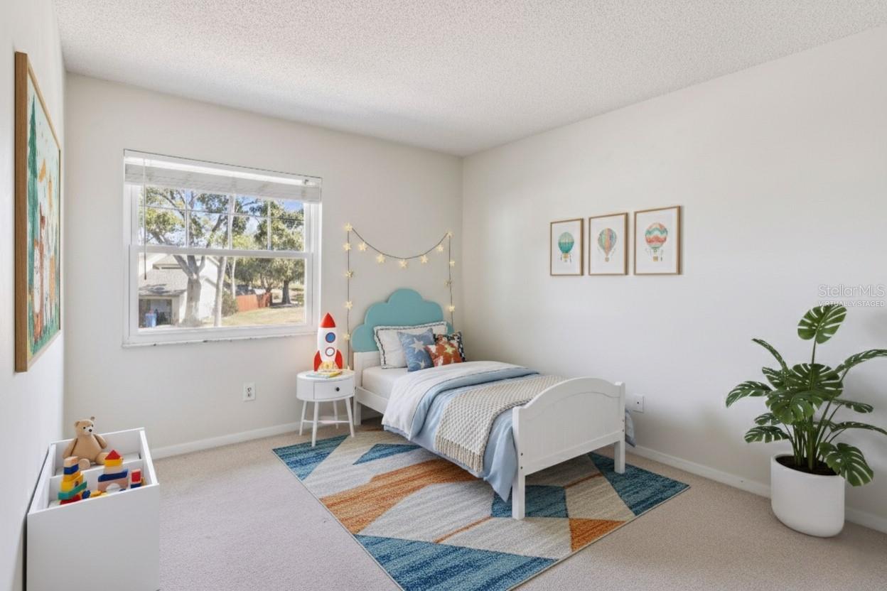 This photo is virtually staged. Bedroom with carpeted flooring, neutral walls, and a window providing natural light. The room is virtually staged with a bed, side table, area rug, and décor to show potential furniture placement.
