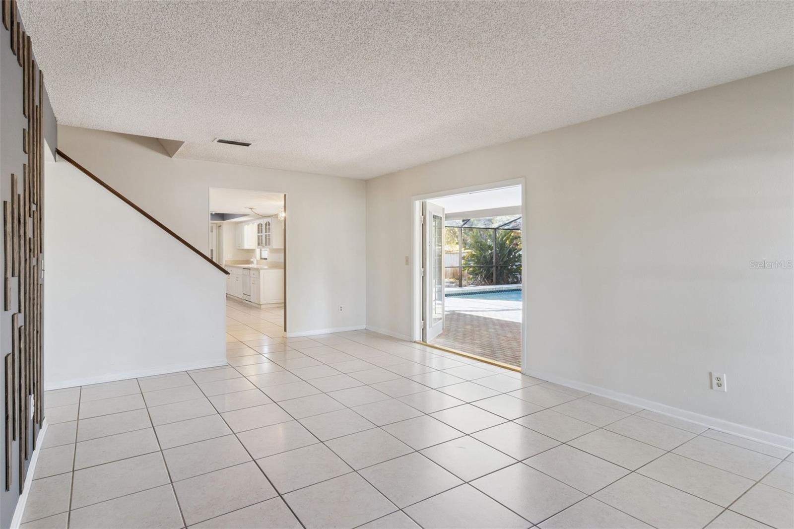 Formal living room with tile flooring, neutral walls, and a large bay window that brings in natural light. The open layout provides flexibility for seating or a sitting area.