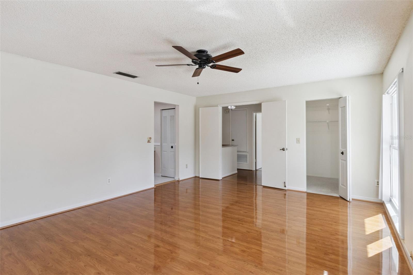 Primary bedroom view highlighting luxury vinyl plank flooring, the entrance to the en-suite bathroom, and access to the large closet.