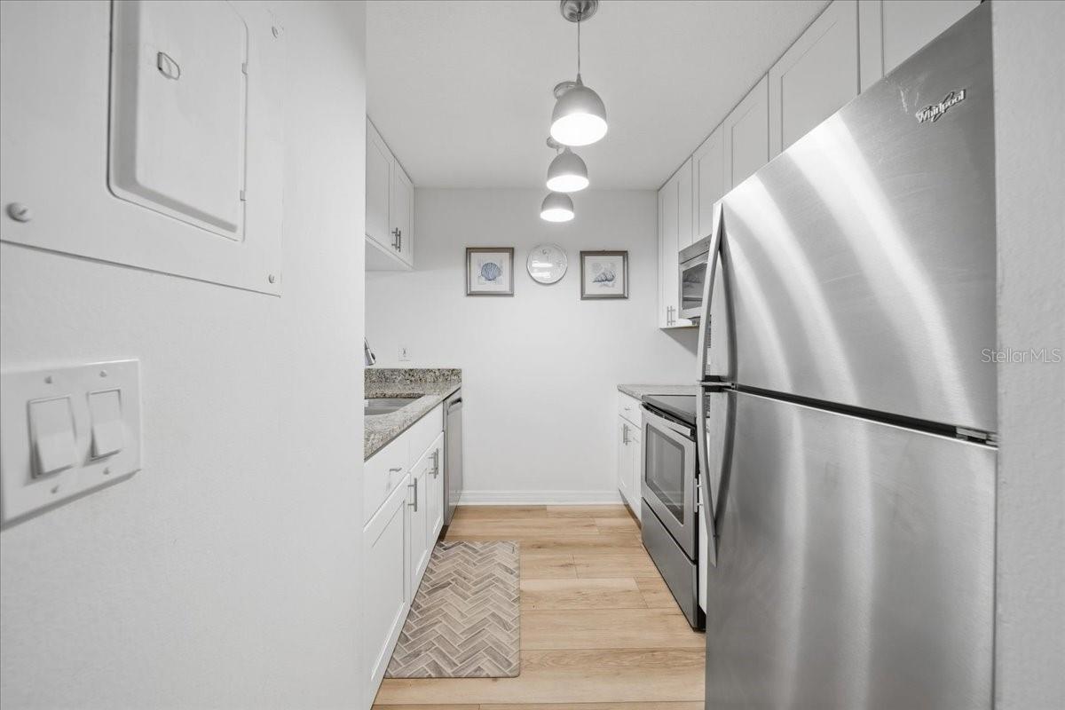 UPDATED KITCHEN with granite countertops, white soft-close cabinets, and stainless-steel Whirlpool appliances.