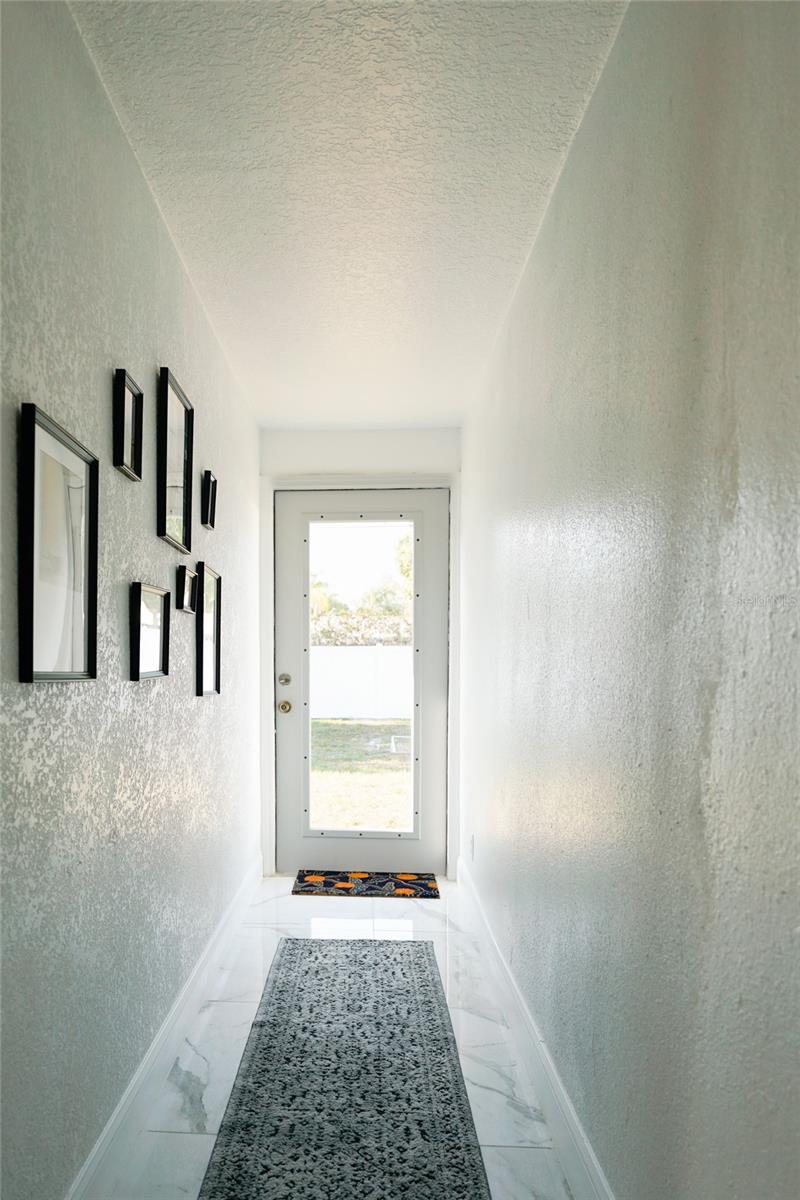 Bright hallway leading to the backyard patio, creating an easy indoor to outdoor flow and convenient access to the pool and entertaining space.