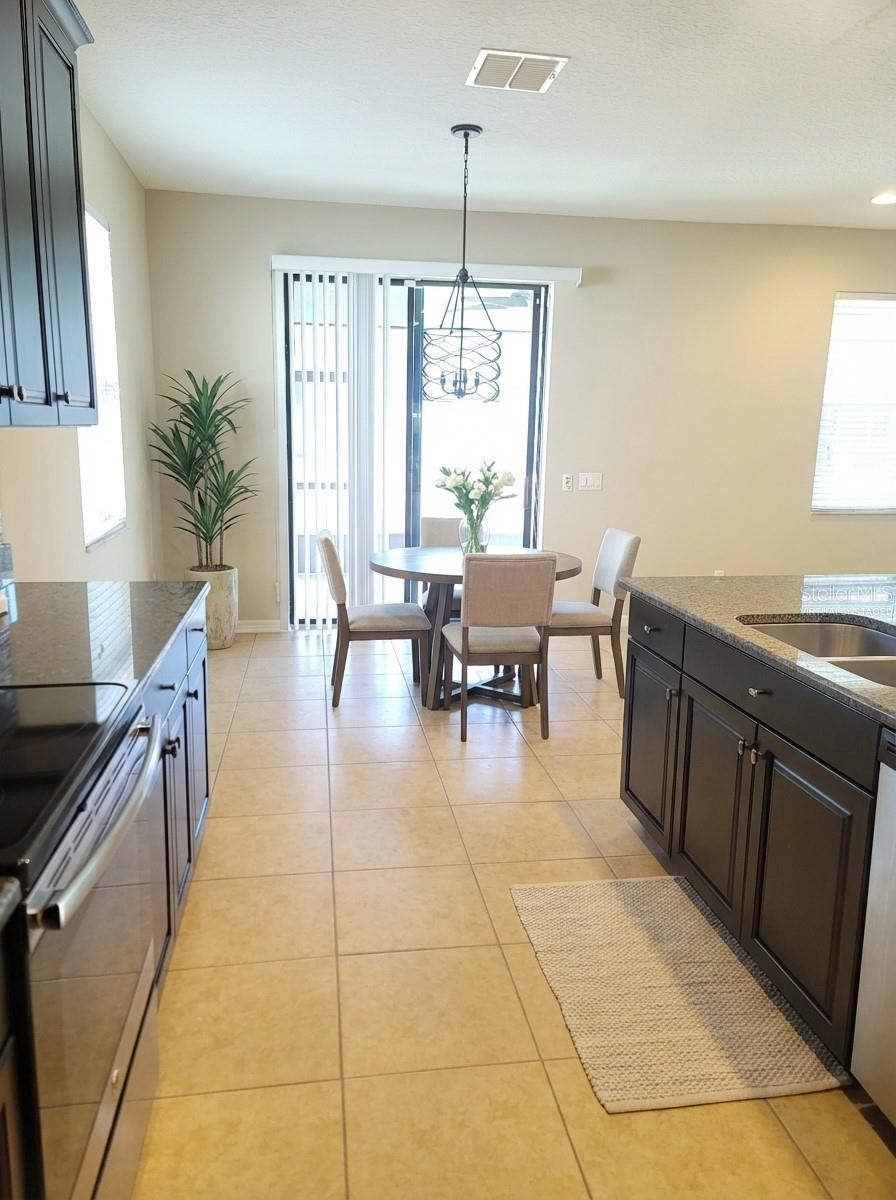 Virtually Staged. Kitchen looking towards dinette area and lanai.