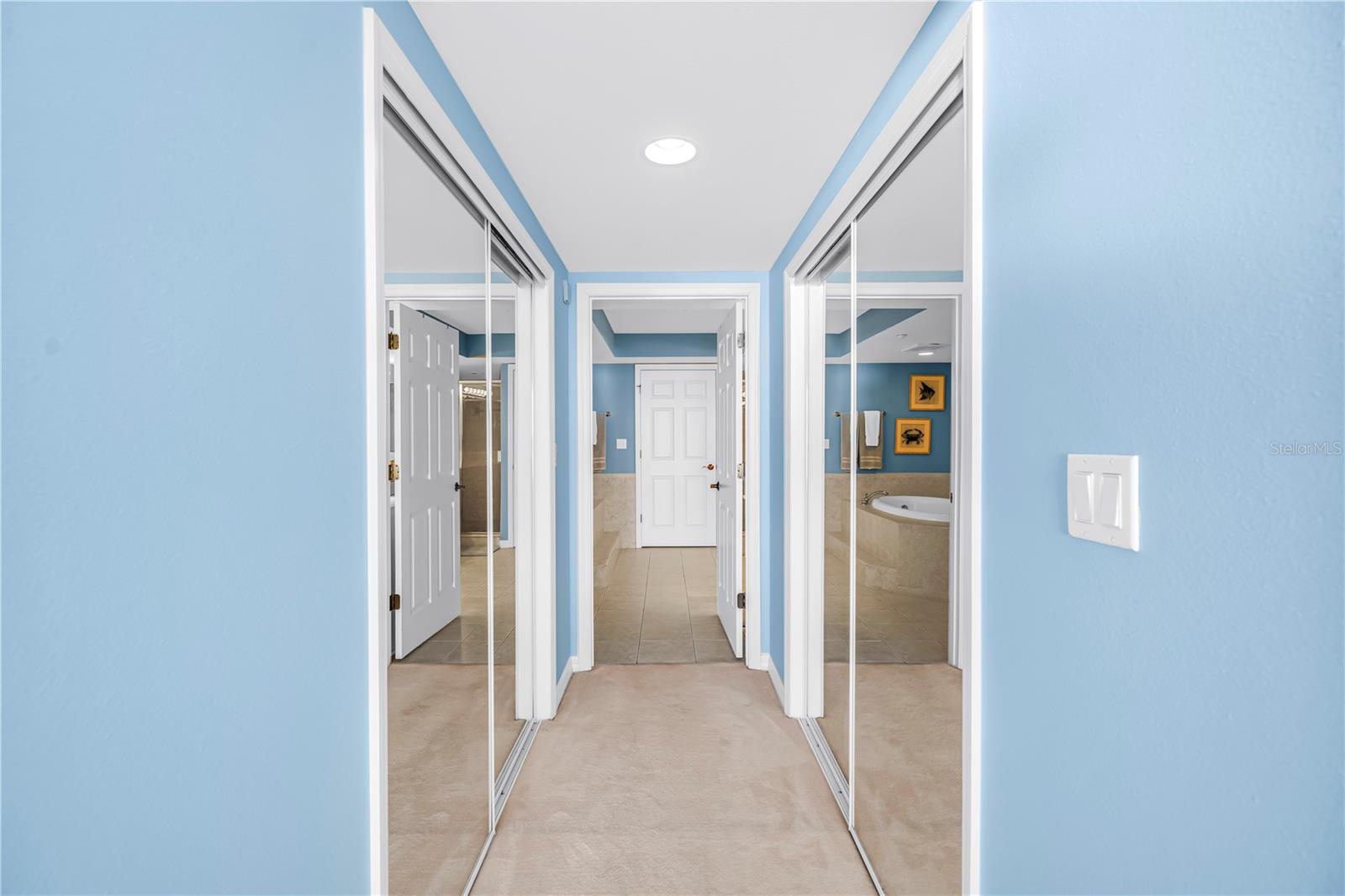 Hallway with dual closets, leading to primary bathroom