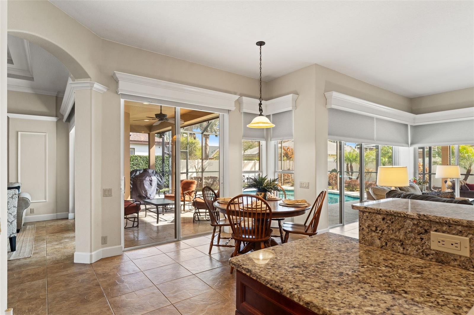 A light-filled breakfast nook with large windows overlooks the backyard and provides direct access to the covered lanai for effortless indoor-outdoor dining.