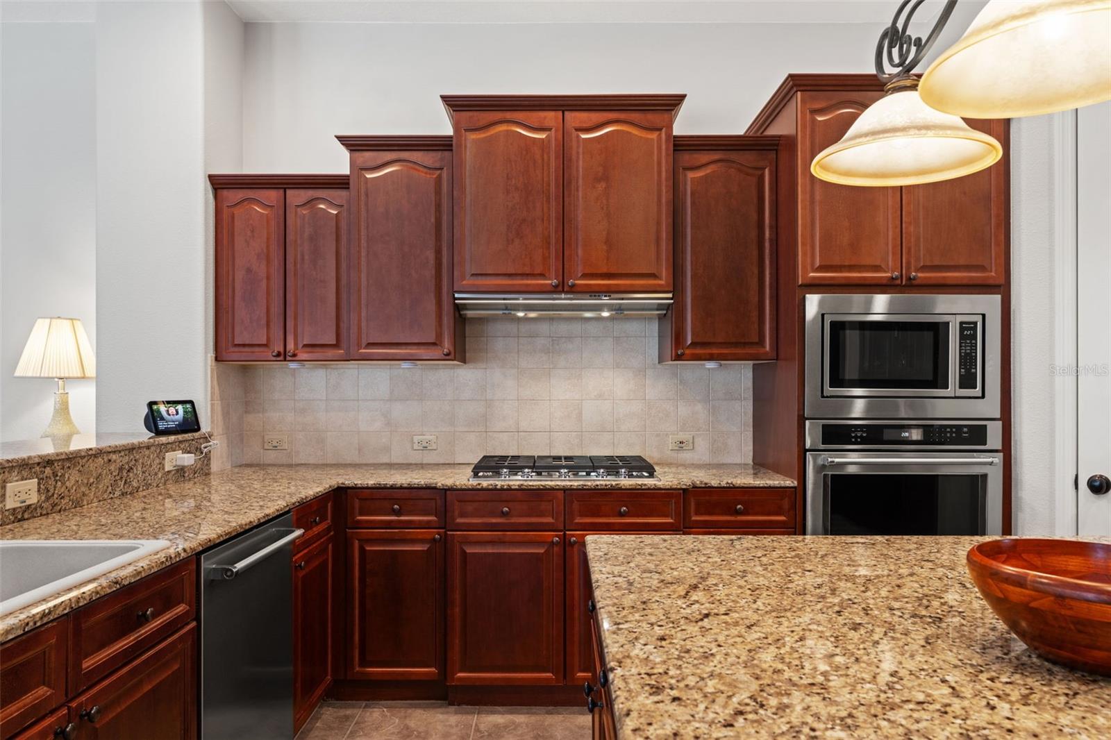 A built-in cooktop with tiled backsplash and double wall ovens provide both convenience and efficiency for meal preparation.