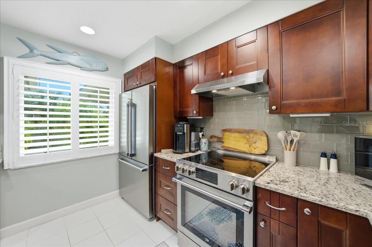 Stunning updated kitchen is well-equipped with stainless-steel appliances including a convection oven, rich cherry wood cabinets with soft closing cabinets and drawers, granite countertops, and beautiful, easy maintenance tile floors that flow into the main living areas.