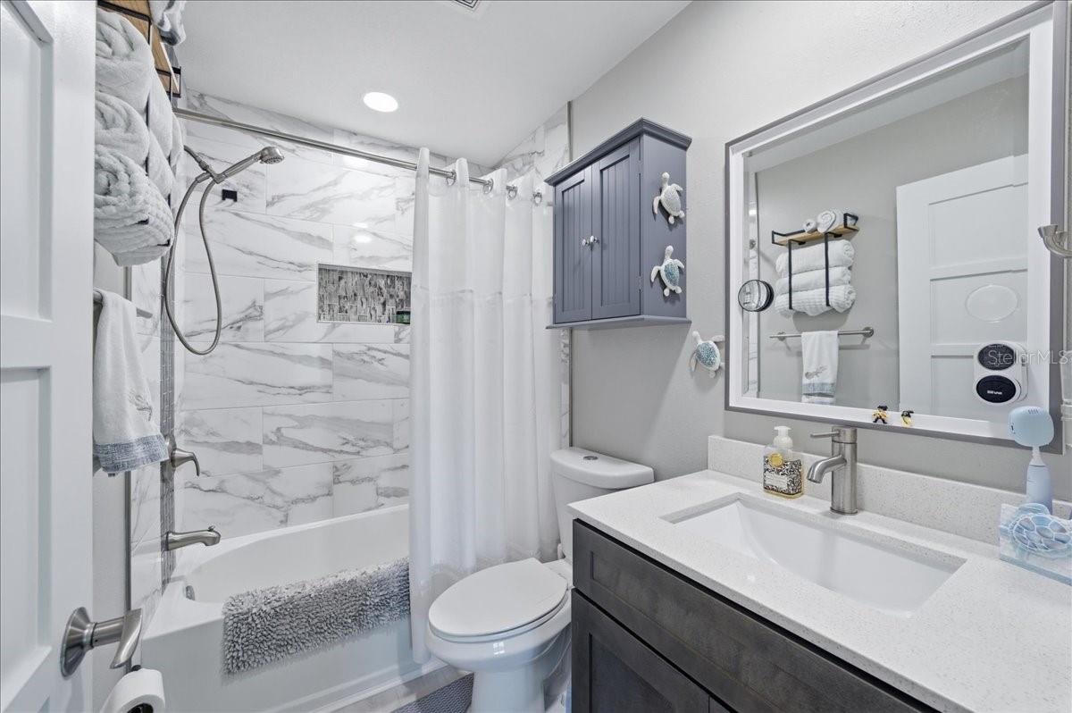 Second bedroom at the front of the unit with its own tastefully updated en-suite bathroom, three windows, beautiful wood-look tile flooring, decorative ceiling fan and California Closet.
