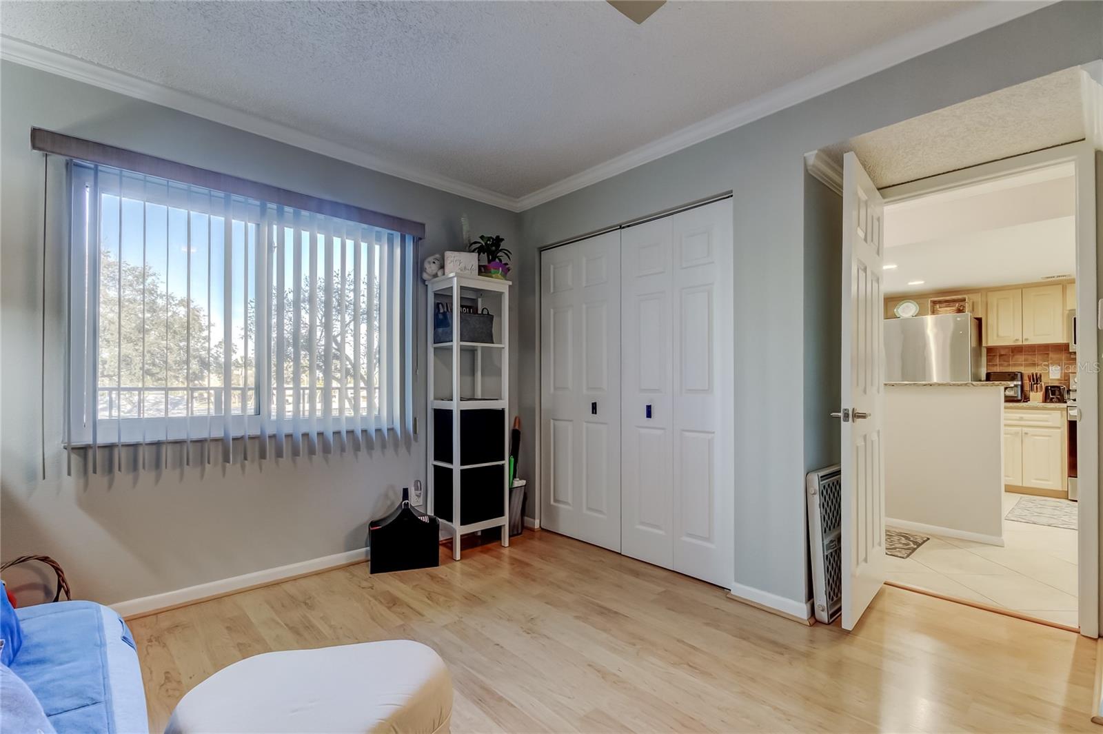 Bedroom 2 with large window, laminate flooring, and crown molding.