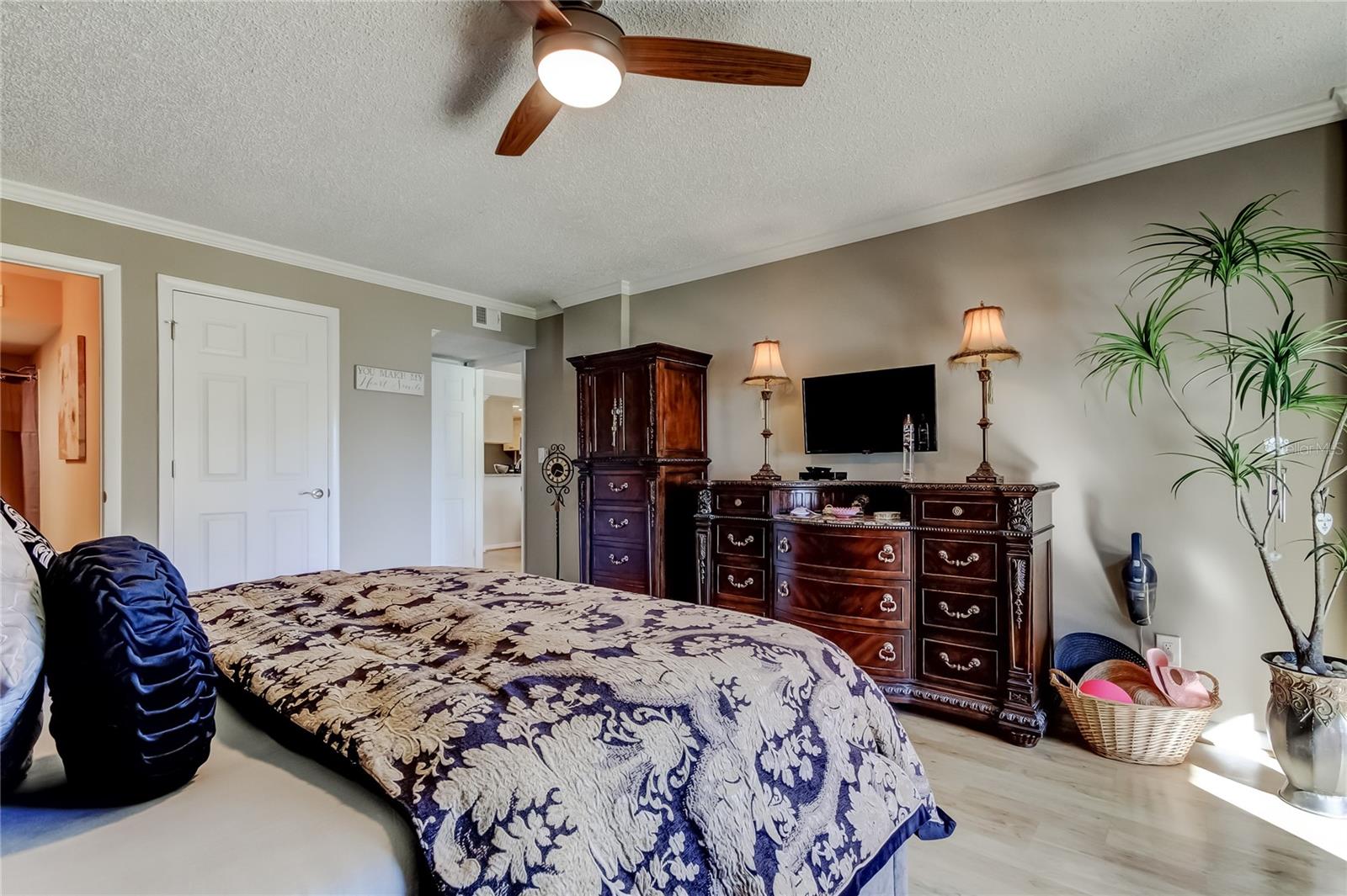 Another view of Master Bedroom with ceiling fan, laminate flooring, crown molding.