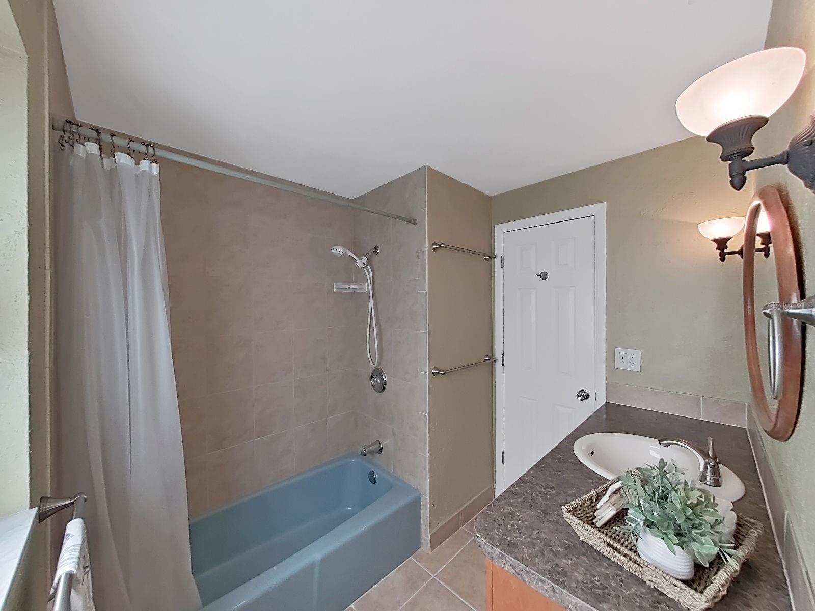 Secondary Bathroom- Tub/shower combo with tiled surround, updated vanity with extended counter space, complimentary mirror & stylish sconce lighting.