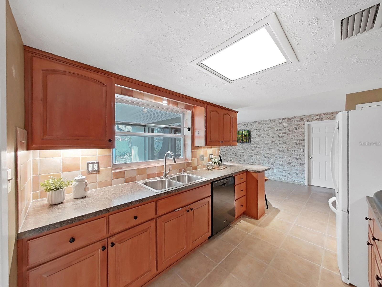 Bright kitchen boasts rich wood cabinetry with select pull out custom drawers. Window fills the space with natural light and offers panoramic backyard views! Undercabinet lighting for tasks and accent.