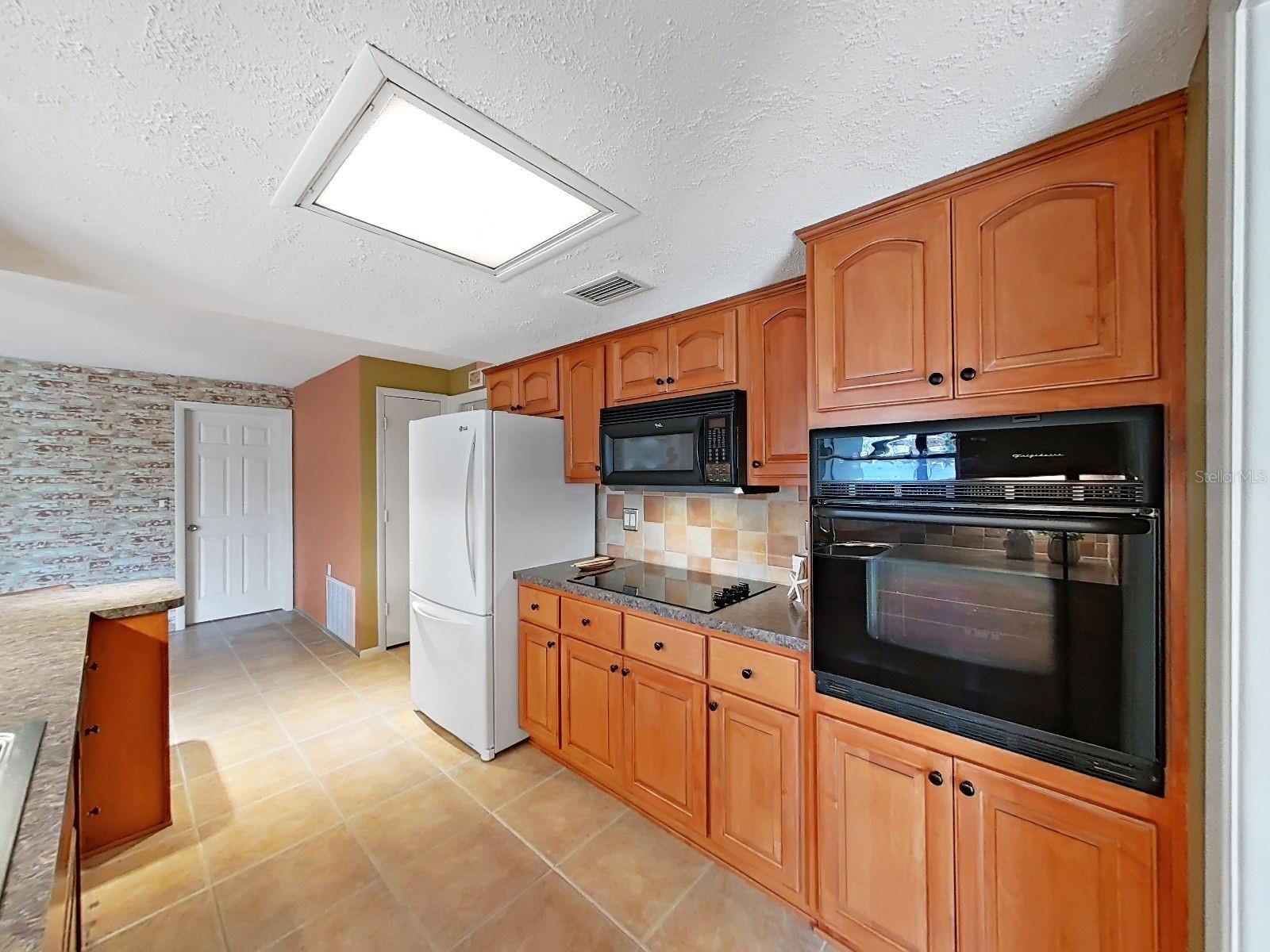 Cooking in this kitchen is a delight! Built-in oven, cooktop, and updated wood cabinetry. Closet pantry with convenient organizer-rounder is on the far side, just beyond the refrigerator.