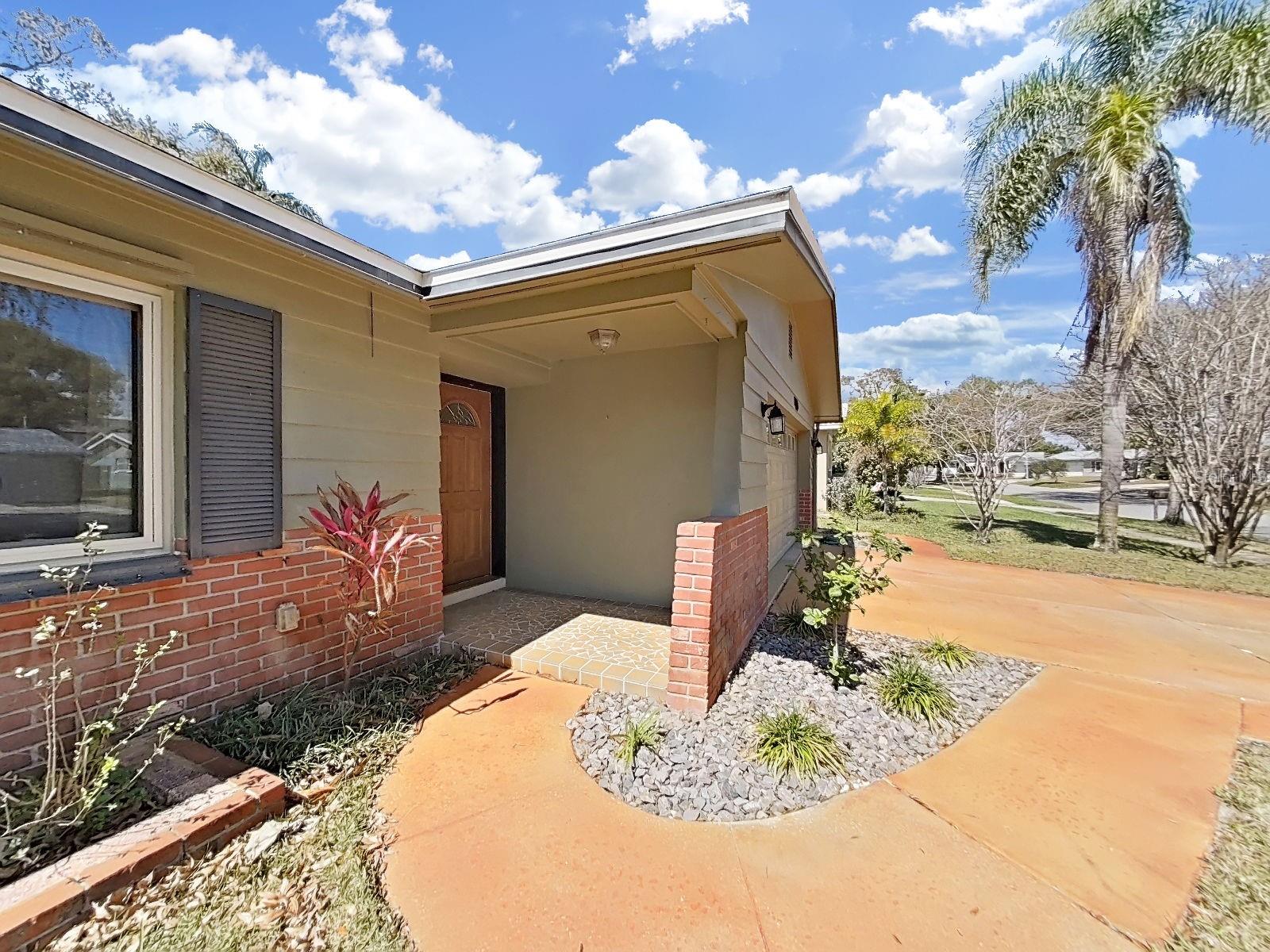 Covered front entry with brick accents, manicured landscaping, & a warm front door welcome you home.