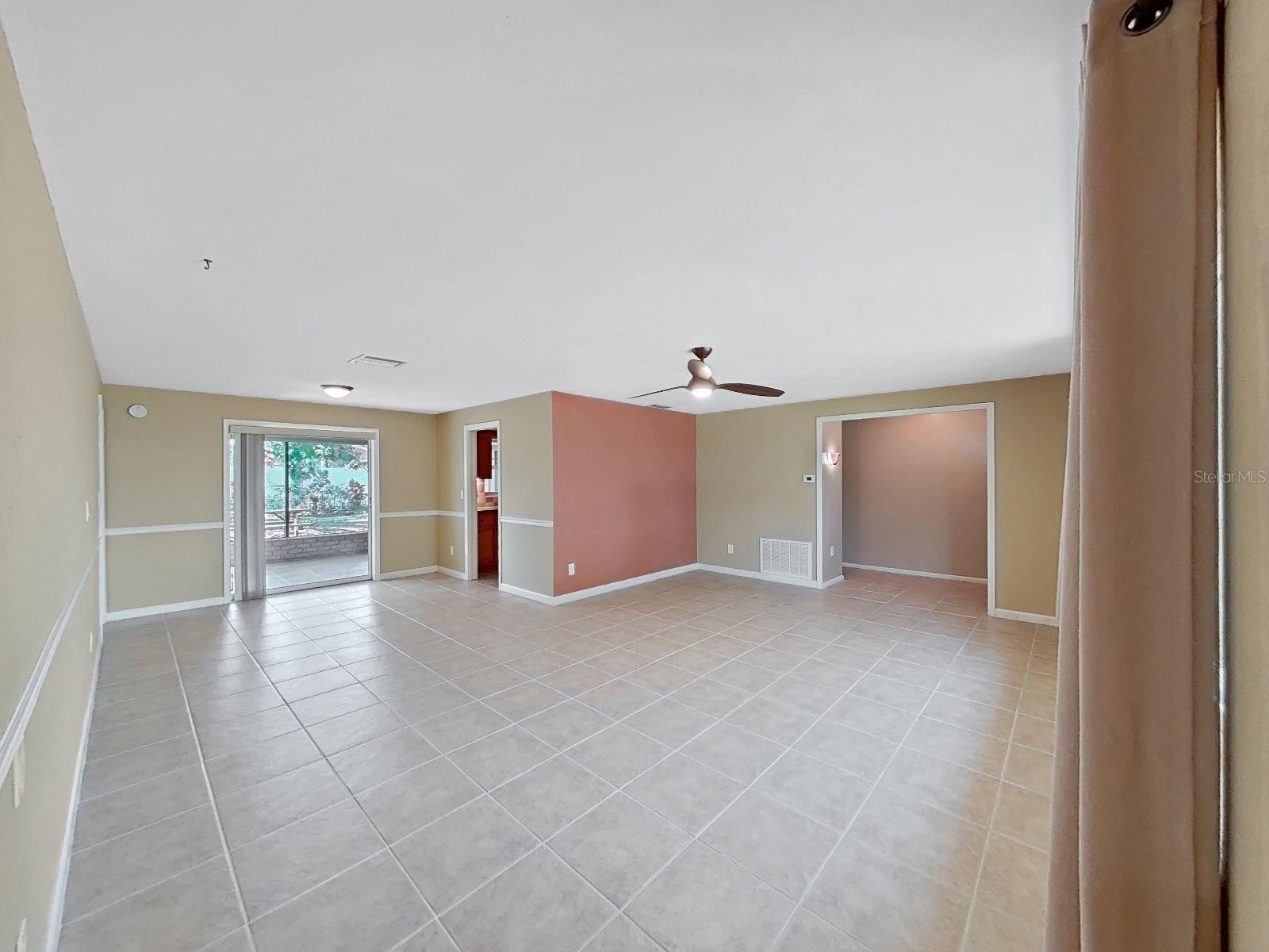 Living & Dining Great Room, with access to the screened rear Lanai & views of the peaceful backyard and greenery.