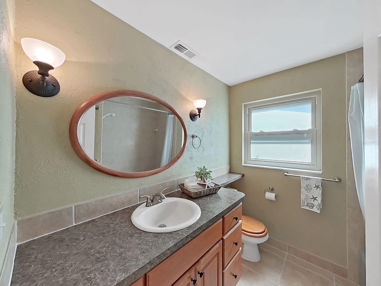Bathroom 2 with extended counter space & updated vanity. Stylish sconce lighting! NEW impact-rated vinyl window. Linen closet just outside the bathroom.