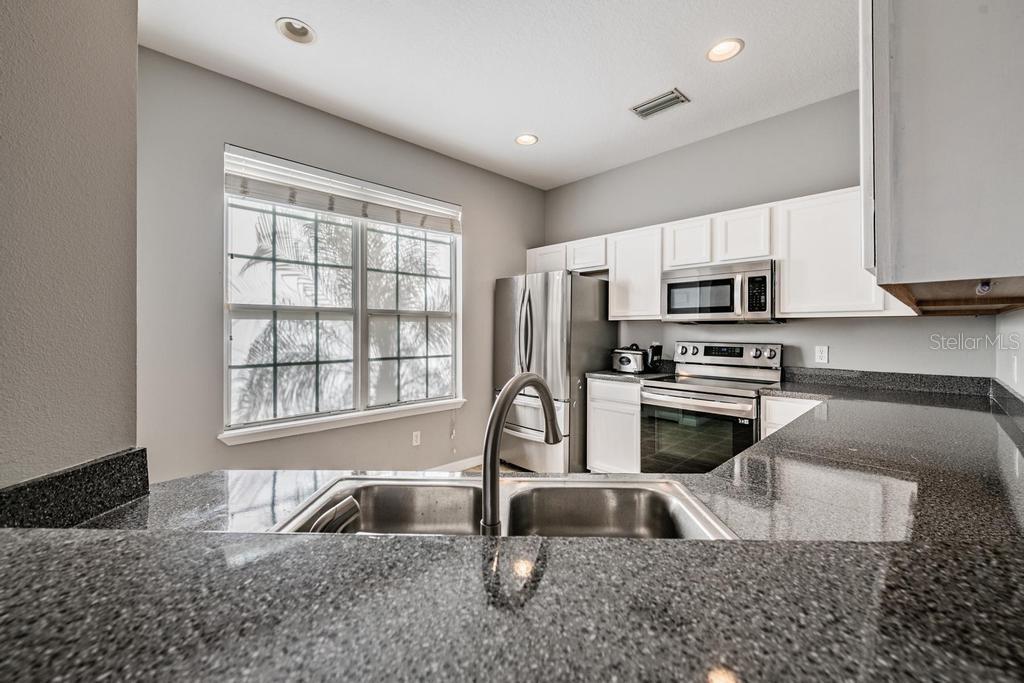 Open Kitchen area with all stainless steel appliances, granite countertops and inset lighting.