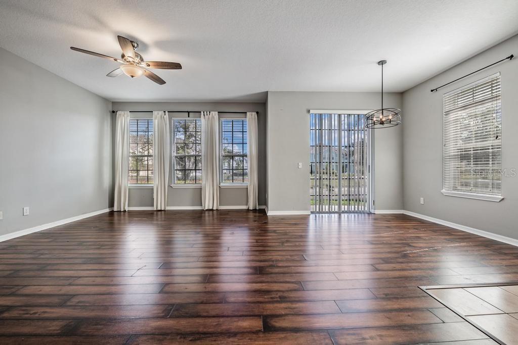 Dining Room/Living Room - lots of natural light and including blinds, drapes, fan and light fixture.