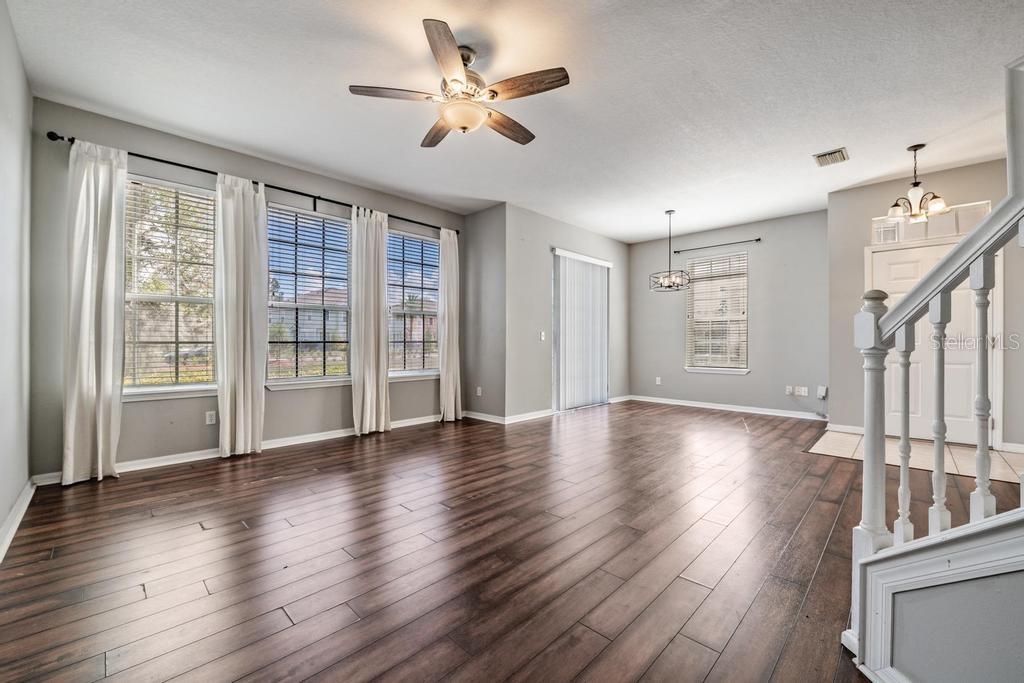 Dining Room/Living Room - lots of natural light and including blinds, drapes, fan and light fixture.