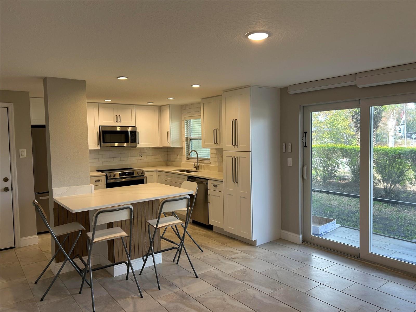 Kitchen features window by sink and sliding glass door for plenty of natural light