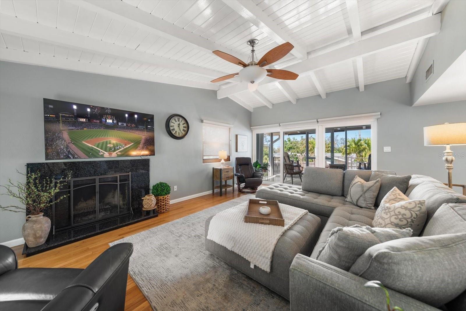 Family room offers charming fireplace, beamed cathedral ceiling and access to upper deck area.