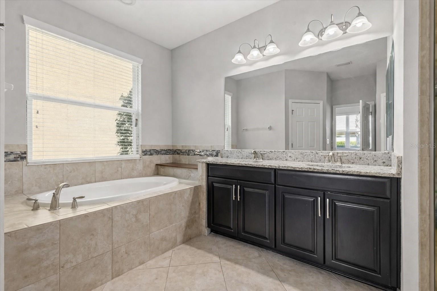 Primary bathroom offers dual sinks, a soaking tub, and shower