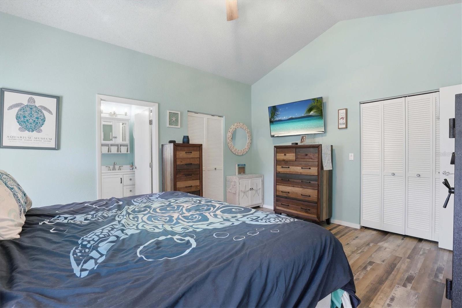Spacious primary bedroom featuring an en suite bathroom, dual closets, and sliding doors opening to the private back porch.
