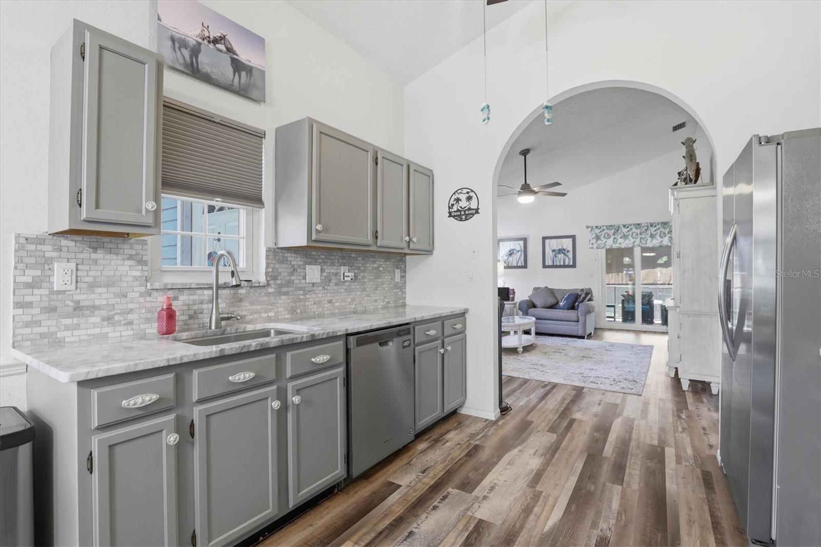 Bright kitchen with granite countertops, newer appliances, tile backsplash, and a window that adds natural light.
