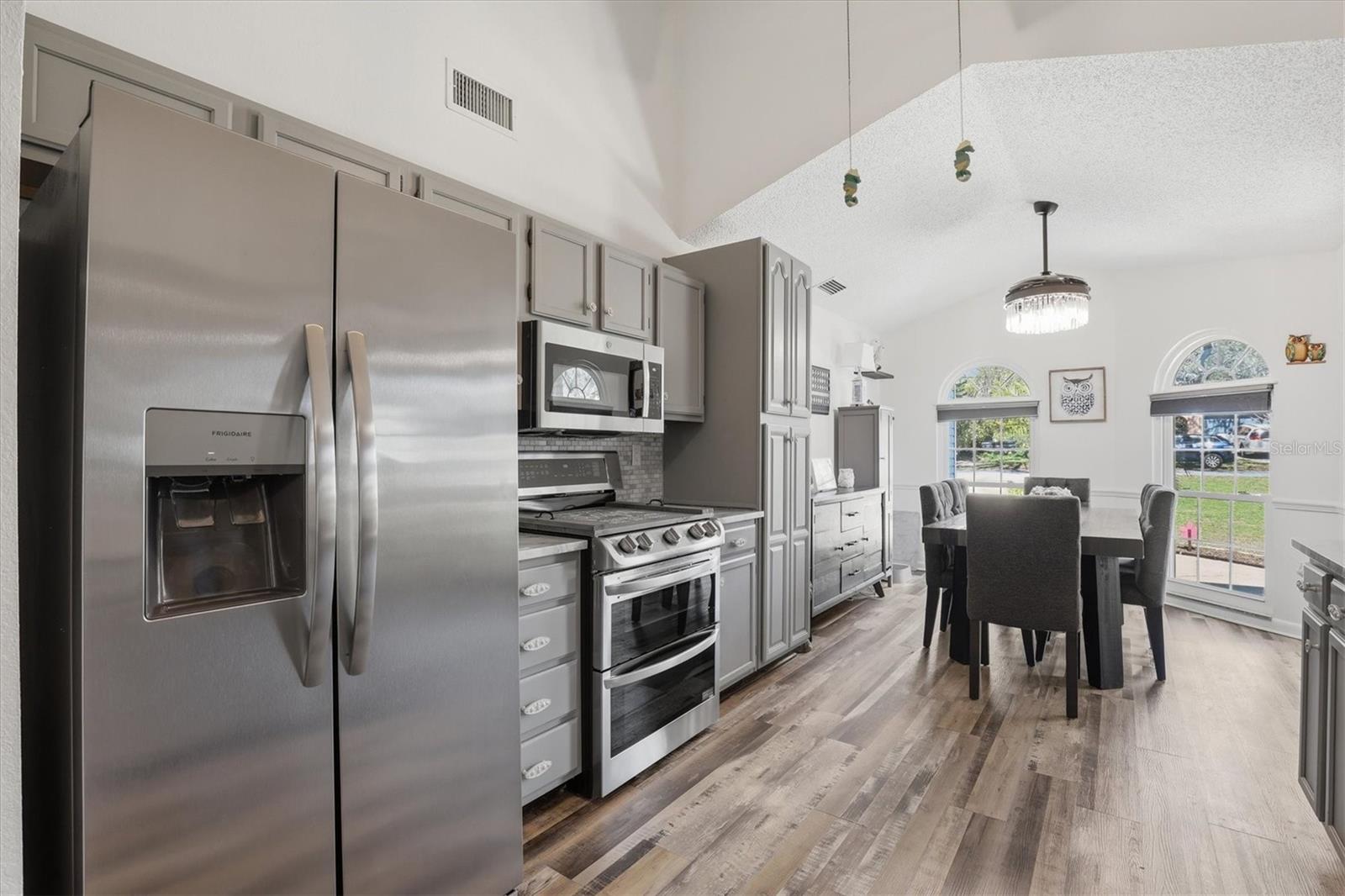 Bright kitchen with granite countertops, newer appliances, tile backsplash, and a dining area with a window that fills the space with natural light.