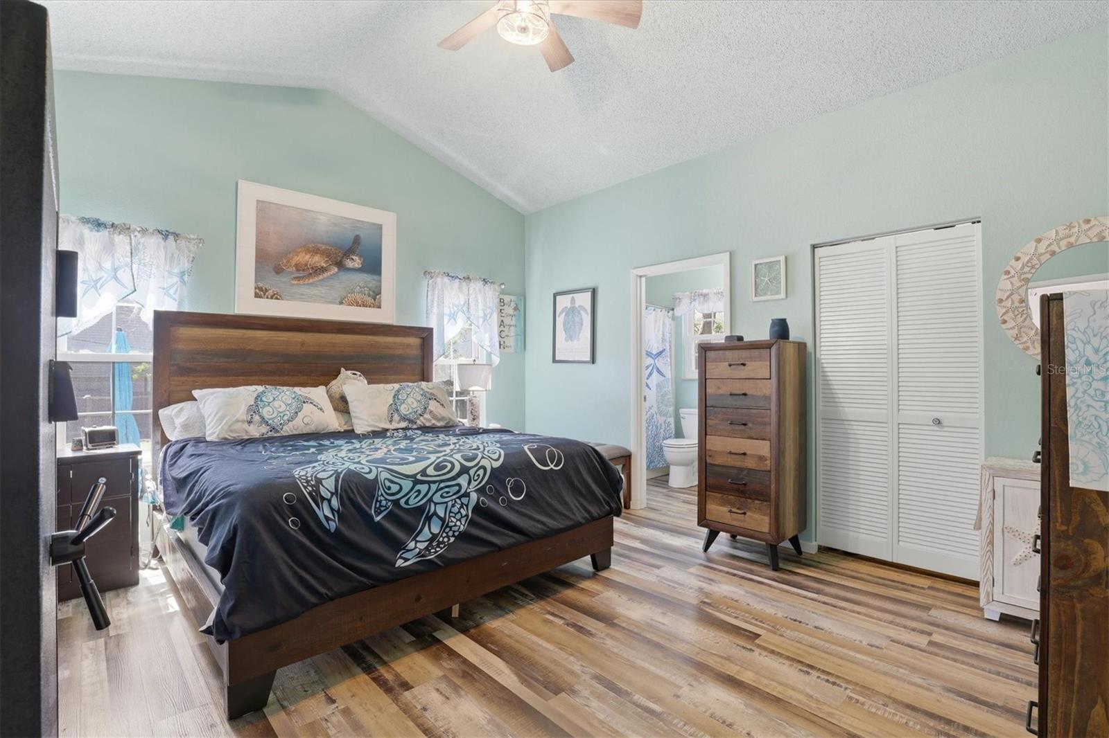 Spacious primary bedroom featuring an en suite bathroom, dual closets, and sliding doors opening to the private back porch.