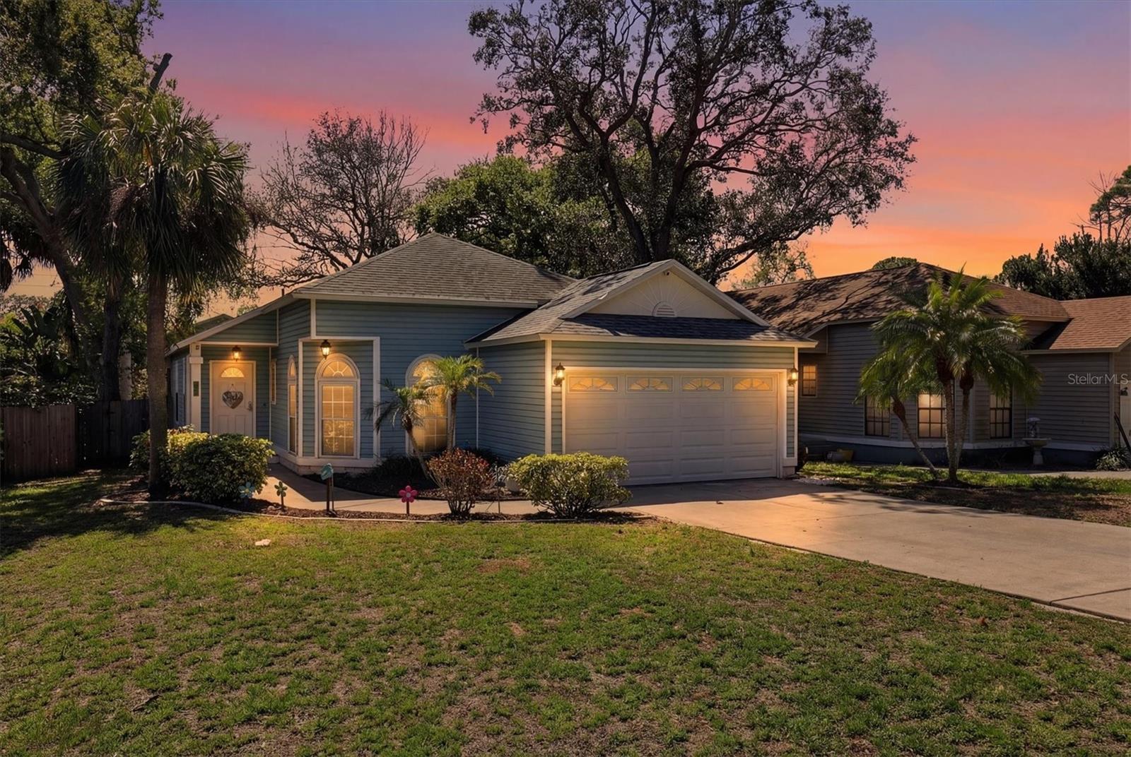Welcoming front elevation with mature landscaping and generous driveway parking in a desirable Tarpon Springs location.