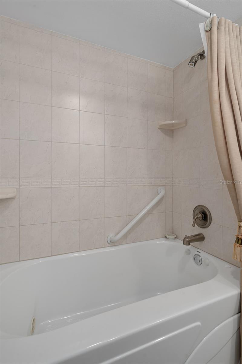 Jetted tub/shower combo in primary suite.  A small storage area is just behind.