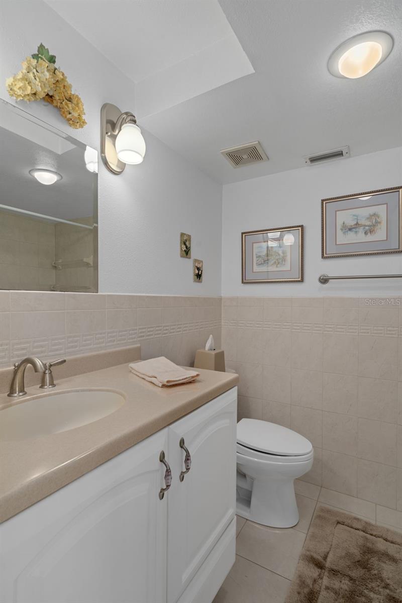 En-suite bath features single vanity with Corian countertop and a storage cabinet + drawer