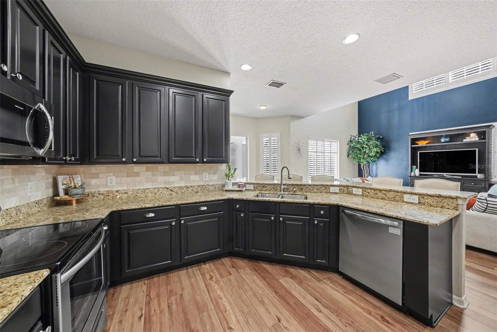 A kitchen perfect for entertaining. Real wooden cabinetry, stainless steel appliances, granite countertops, and a large breakfast bar open to the family room.