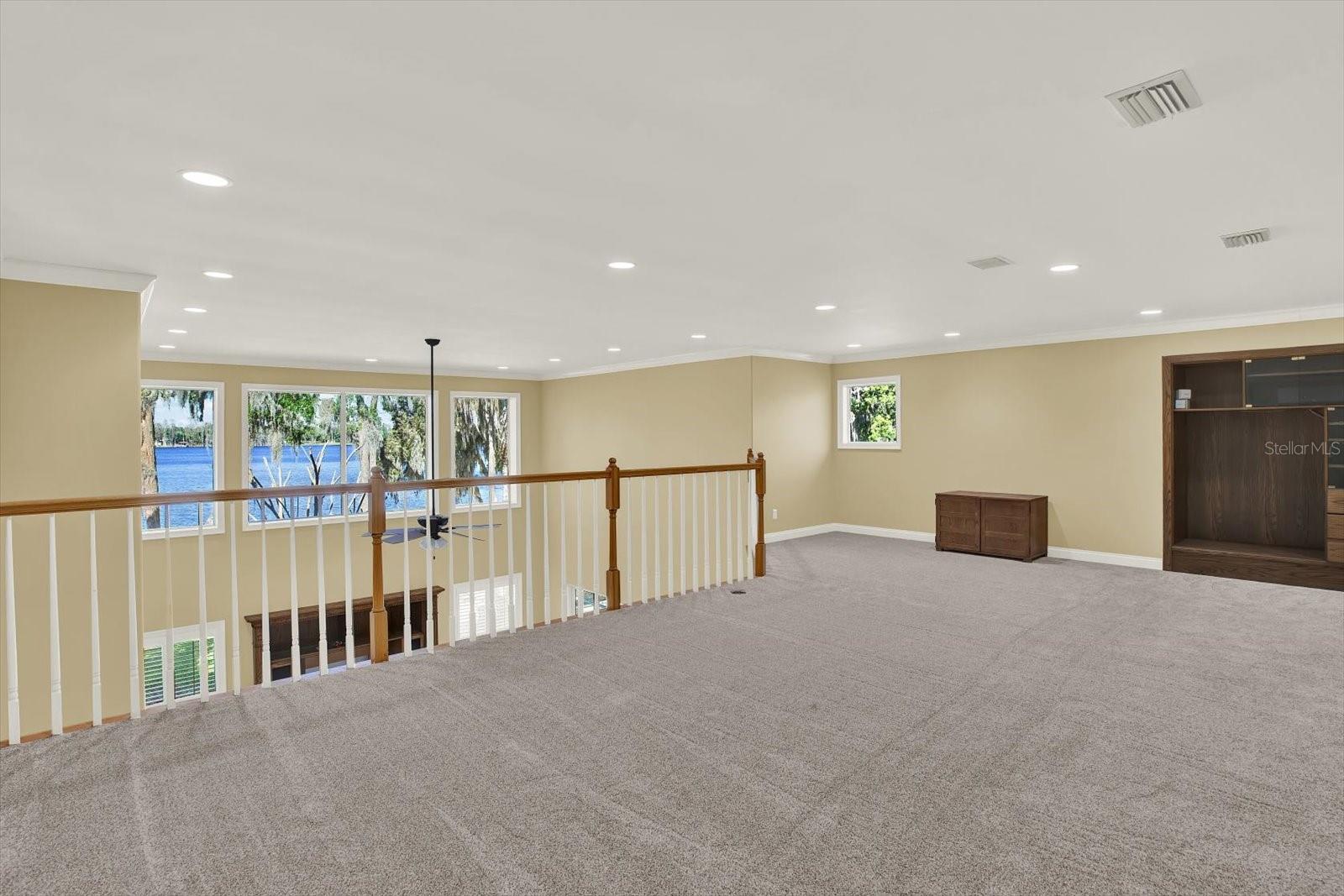 The expansive open loft features amazing lake views, natural light, a built in TV console, and a wet bar.